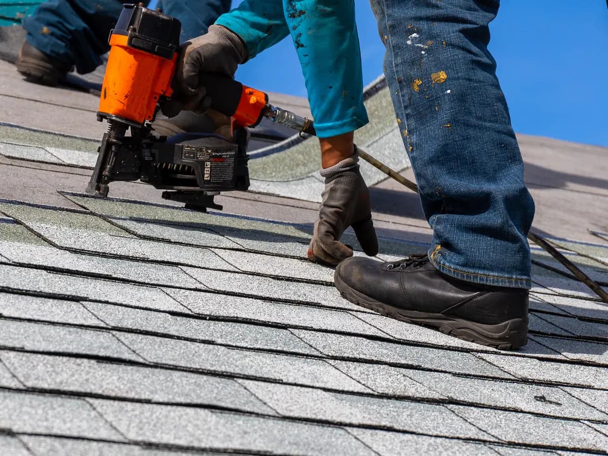 Roofer nailing asphalt shingles